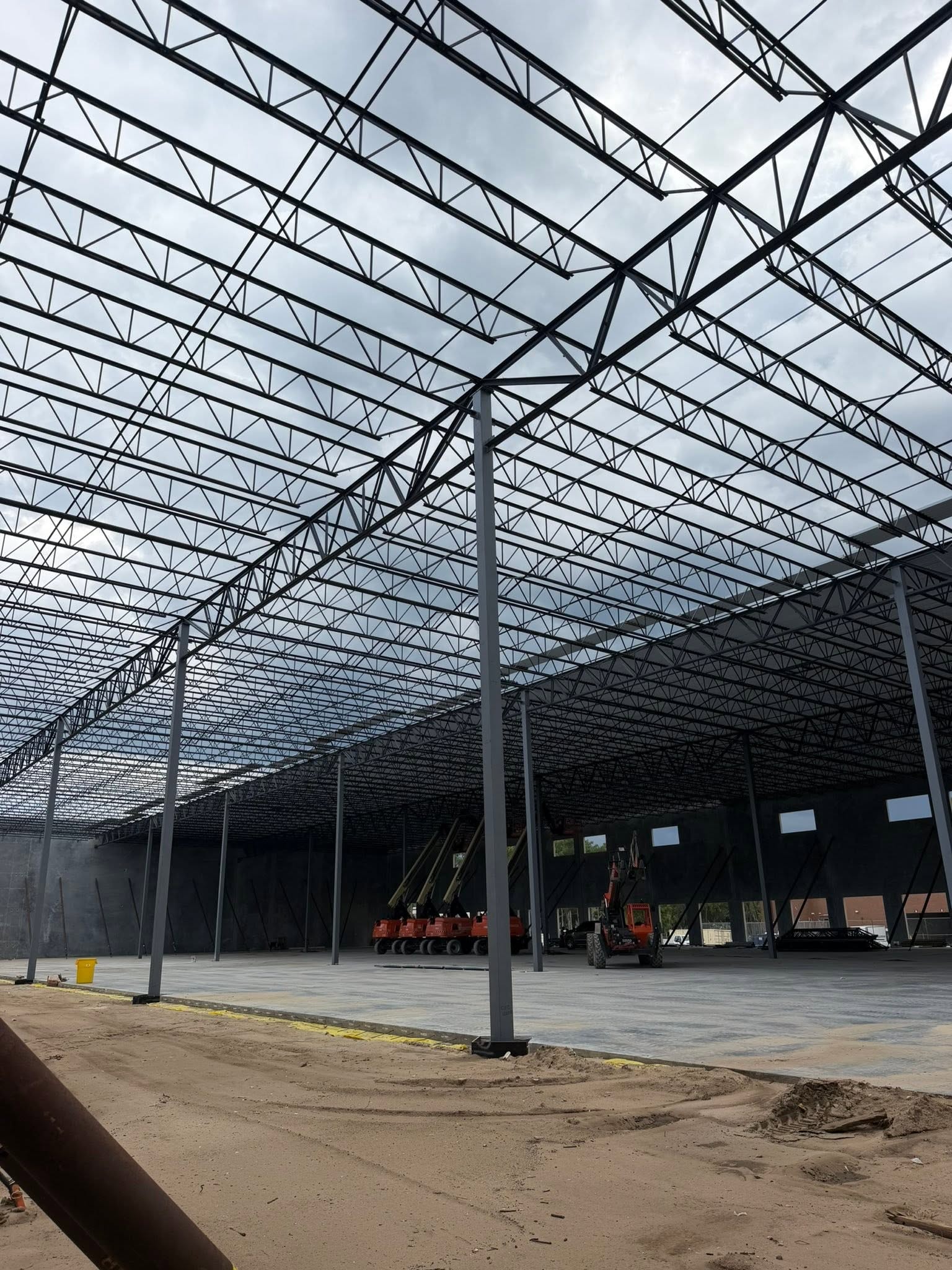 Steel workers installing metal roof panels on a large steel frame